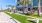 a building with palm trees and a lawn with chairs and tables