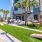a building with palm trees and a lawn with chairs and tables